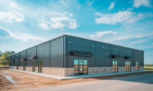 3,000 Sq Ft prefabricated office-warehouse metal building with black siding, stone accents, large glass doors, and awnings in a new business park