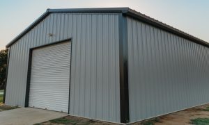30x40x12 metal building garage with a clear-span design, gray steel siding, black trim, and a roll-up door for vehicle or equipment storage