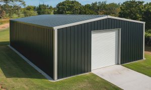 35x40 metal building with dark green steel siding, a white roll-up door, and a concrete driveway, set on a grassy lot