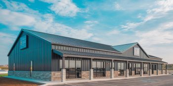 35x70 retail metal building with black steel siding, stone wainscoting, large storefront windows, and a paved parking lot in Chicago IL