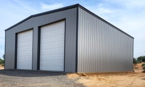 40x40 metal building garage workshop combo with two white overhead doors, gray steel siding, and black trim on a gravel pad