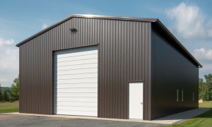 36x40 pre-engineered metal building with brown steel siding, a tall white roll-up door, and side entry, set on a concrete slab