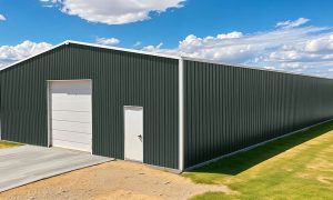 50x75 Commercial metal building with dark green siding, tall white overhead door, side entry, and a concrete driveway