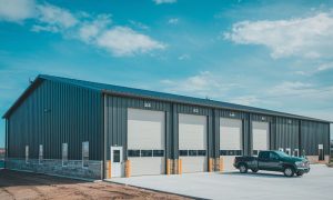 50x100 Auto maintenance metal building with five large service bays, attached office, dark steel siding, and parking area in Phoenix, Arizona