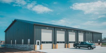 50x100 Auto maintenance metal building with five large service bays, attached office, dark steel siding, and parking area in Phoenix, Arizona
