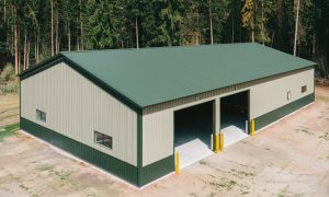 60x50 red iron metal building with green roof, beige siding, two large open bays, and a concrete floor, set in a wooded area