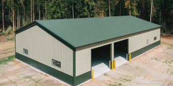 60x50 red iron metal building with green roof, beige siding, two large open bays, and a concrete floor, set in a wooded area