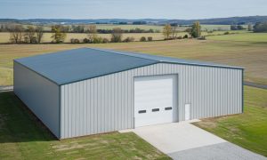 80x80 metal building with light gray PBR siding and a paved driveway, set in open farmland