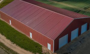 Aerial view of a 40x100 farm storage steel building painted red with a gabled roof and side entries on a rural lot