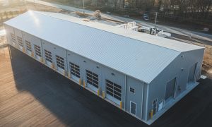 Auto repair shop / garage metal building (50x120) with multiple bays, gray PBR panel siding, and a paved lot near a highway