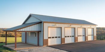 Garage metal building with four parking bays in white and brown, a covered lean-to, and a paved driveway in a rural setting