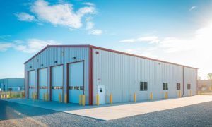 55x70 commercial metal building used as a garage with red trim, and concrete apron in a business park