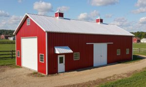 small red and white steel barn with large overhead door and sliding doors