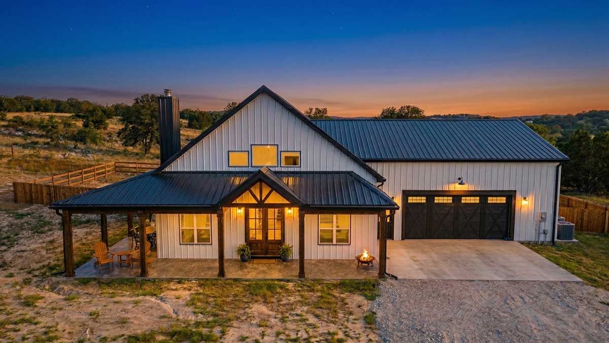 A white farmhouse barndominium with black trim, metal siding and double garage located in Michigan