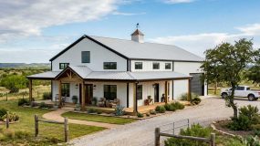 A simple barndominium home in white and black with wrap around porch located in west Texas