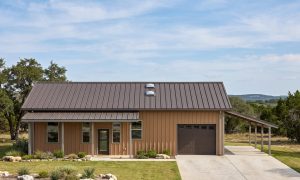 The Bramble 40×50 barndominium front elevation (south on the plan), photoreal render: 4:12 gable, the 26 foot front porch and one overhead door into the 1-car garage