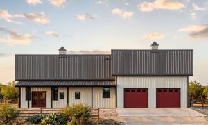 The Brazos 40×70 barndominium front elevation (south on the plan), photoreal render: 6:12 gable, the 40 foot front porch, two cupolas and two overhead doors into the 2-car garage