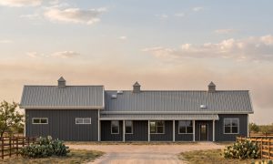 The Caprock 40×90 barndominium front elevation (south on the plan), photoreal render: 5:12 gable, the 46 foot front porch and three cupolas