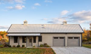 The Fieldstone 40×60 barndominium front elevation (south on the plan), photoreal render: 4:12 gable, the 24 foot front porch, two cupolas and two overhead doors into the 2-car garage