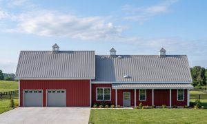 The Hearth 50×80 barndominium front elevation (south on the plan), photoreal render: 6:12 gable, the 34 foot front porch, three cupolas and two overhead doors into the 2-car garage